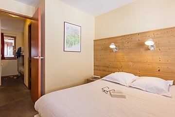 A bed with a book and glasses on it