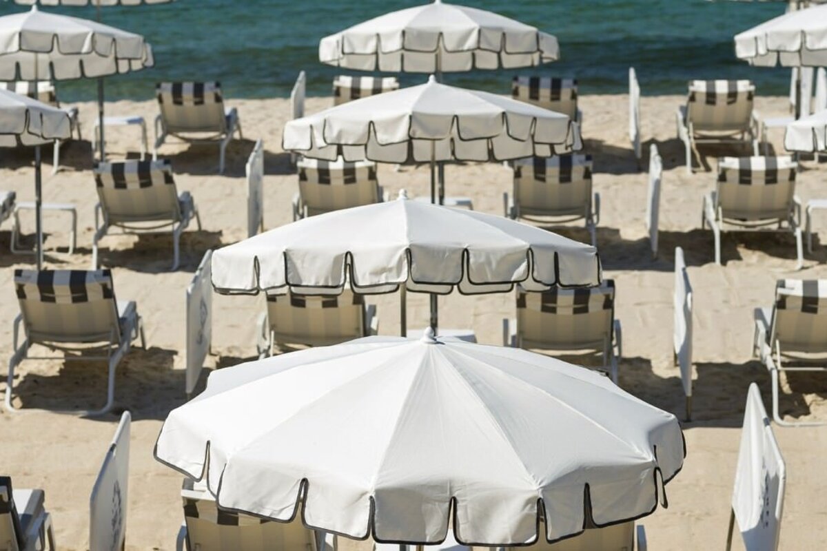 A row of white umbrellas and chairs on a beach