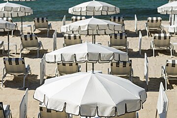 A row of white umbrellas and chairs on a beach