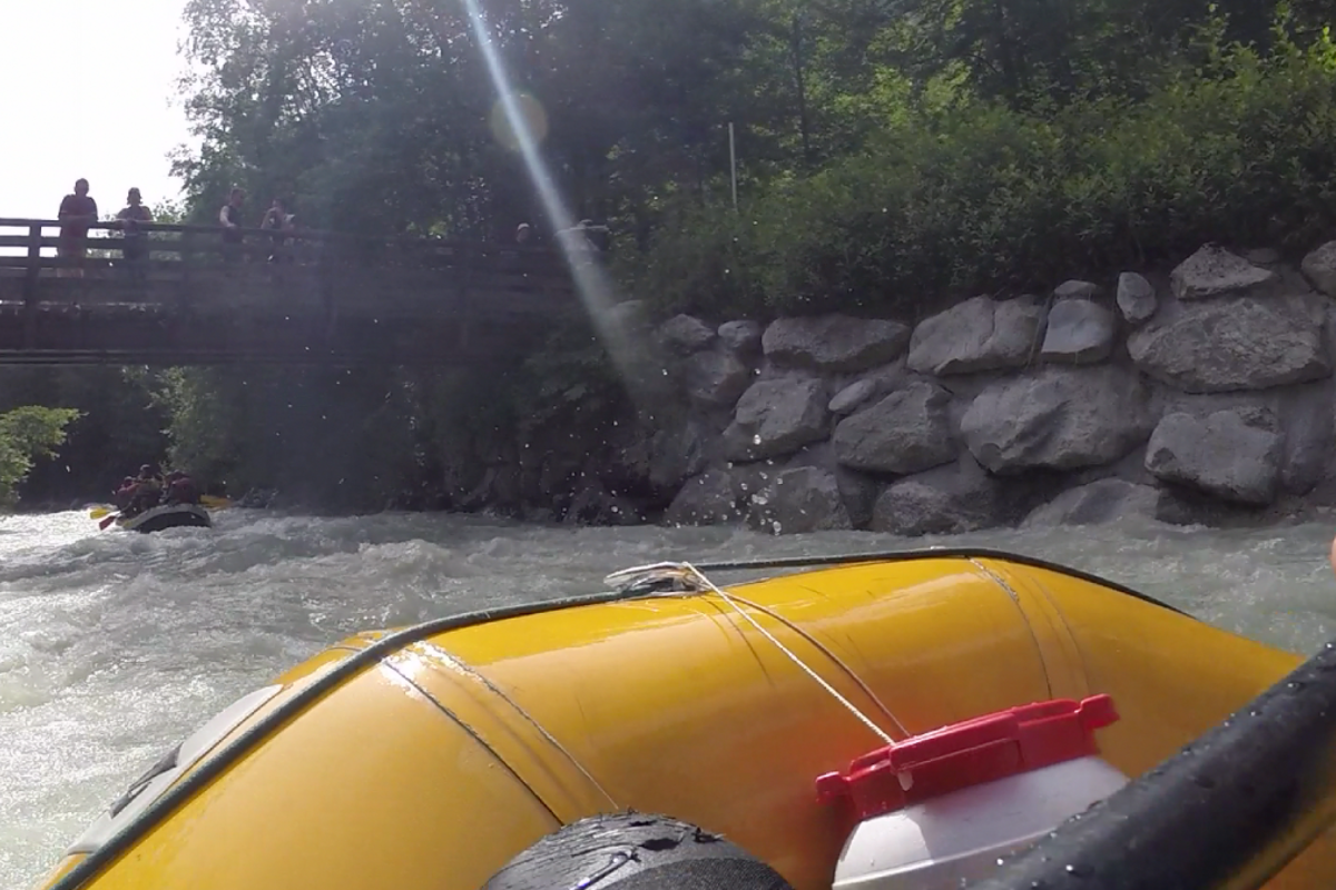 A group of people are rafting down a river in a yellow raft