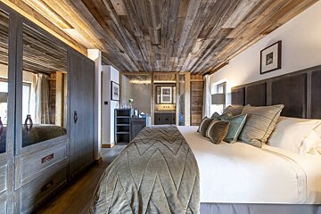 A bedroom with a wooden ceiling and a large bed