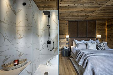 A bedroom with a walk in shower and a bed