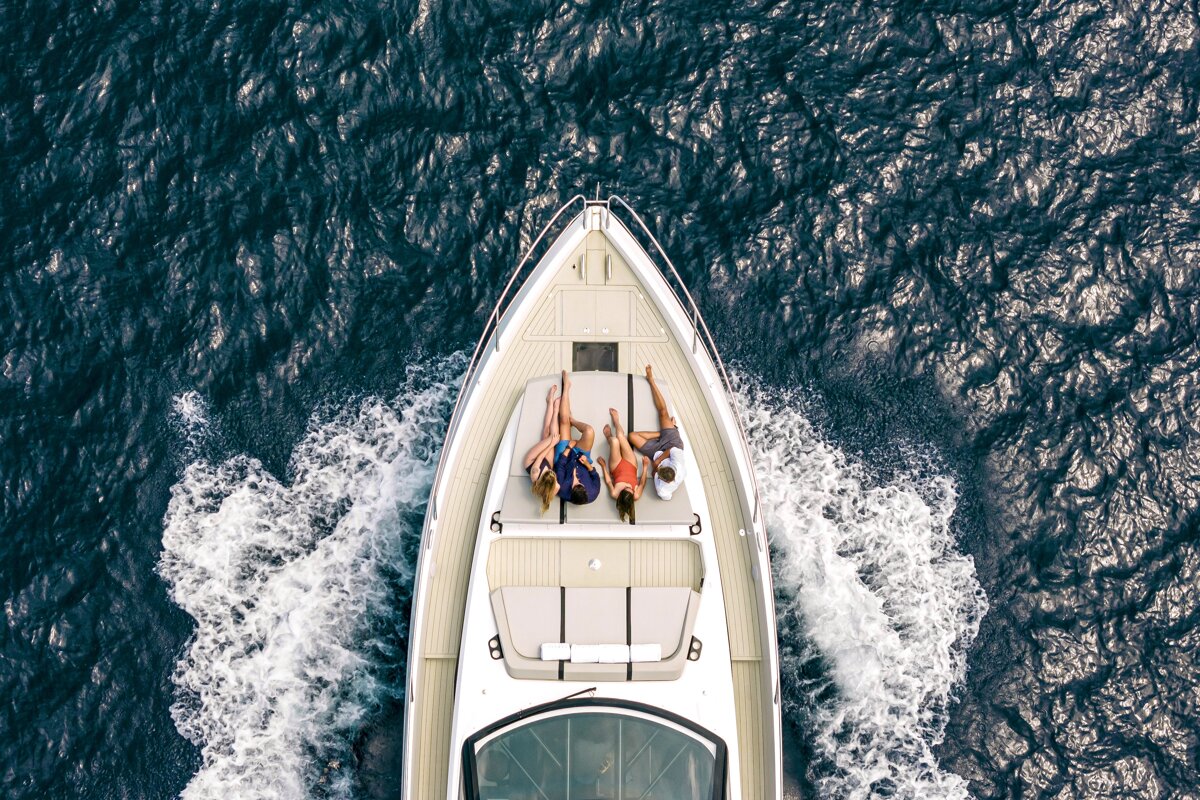 Two women are laying on the front of a boat in the ocean