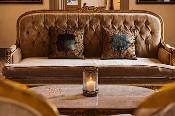 A couch with two pillows and a candle on a table