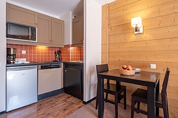A small kitchen with a table and chairs and a whirlpool refrigerator