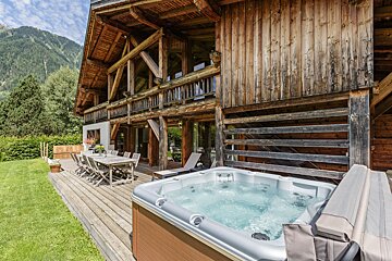 A large wooden house with a hot tub in front of it