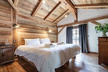 A bedroom with a wooden ceiling and a large bed
