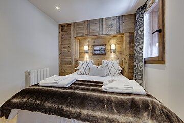 A bedroom with a painting of a moose on the wall above the bed