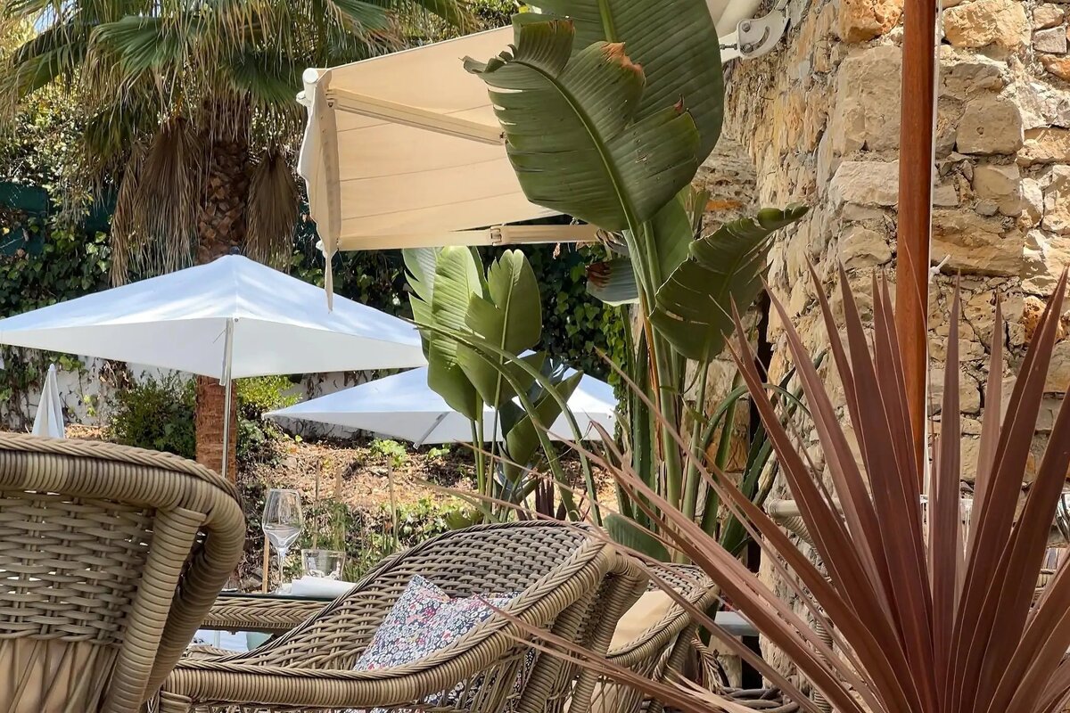 A row of wicker chairs and umbrellas in front of a stone wall