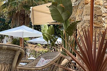A row of wicker chairs and umbrellas in front of a stone wall
