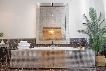 A bathroom with a large mirror above a bathtub