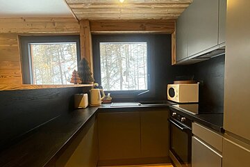 A kitchen with black cabinets and a white microwave