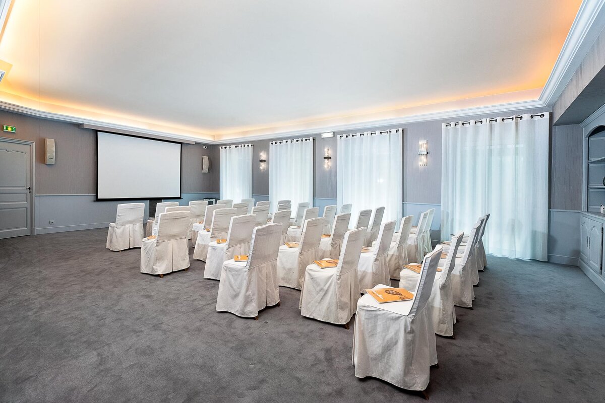 Rows of white chairs in front of a projector screen