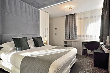 A hotel room with a bed and a desk