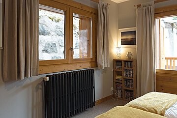 A bedroom with two beds and a bookshelf with books on it