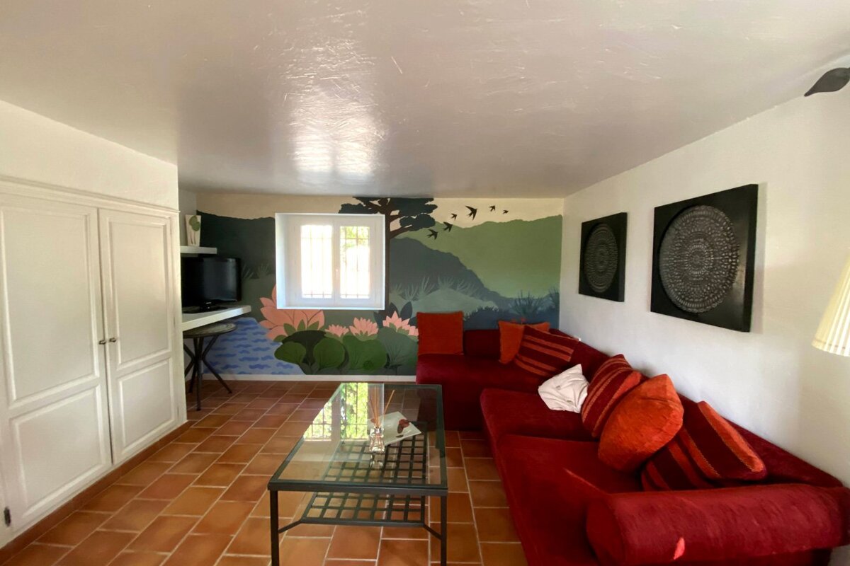A living room with a red couch and a painting on the wall