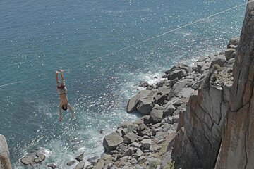 A man is hanging upside down over a body of water