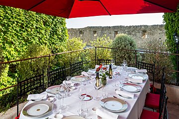 A table with plates and wine glasses under a red umbrella