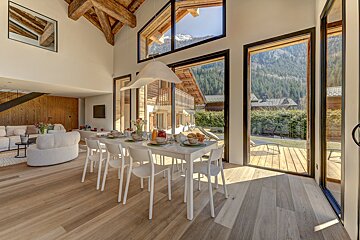 A dining room with a table and chairs and a view of the mountains