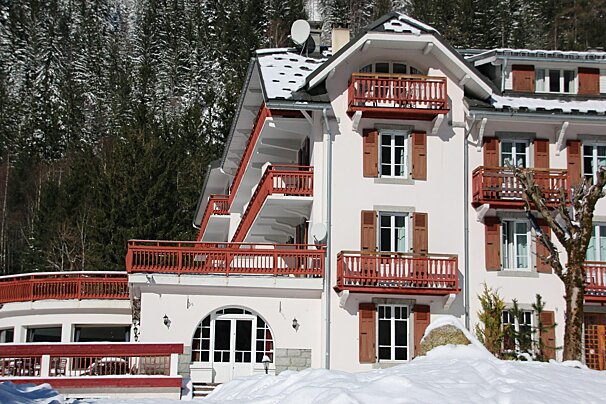 A snowy parking lot with a hotel in the background