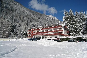 A snowy parking lot with a hotel in the background