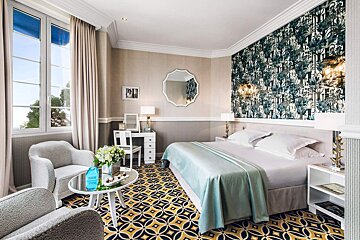 A hotel room with a large bed and a chair
