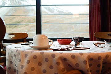 A table with a polka dot table cloth and a cup on it