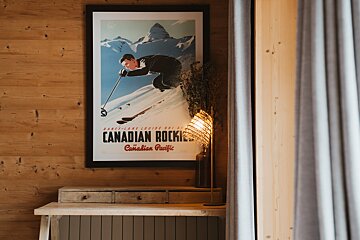 A canadian rockies poster hangs on a wooden wall