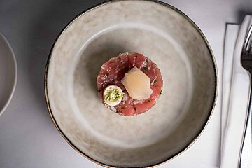 A white plate with a small piece of meat on it