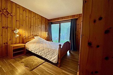 A bedroom with wood paneled walls and a bed