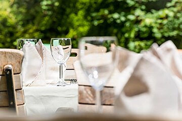 Two wine glasses are on a table with a napkin and a fork