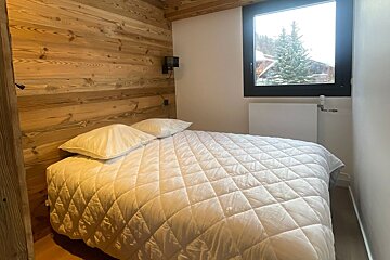 A small bedroom with a bed and a window