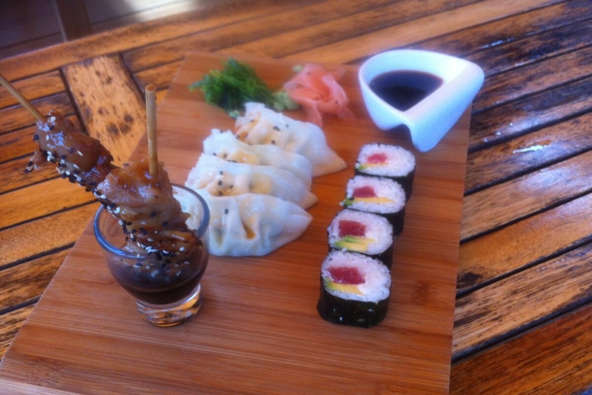 a plate of oriental snacks with dips