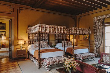 A bedroom with two canopy beds and a couch