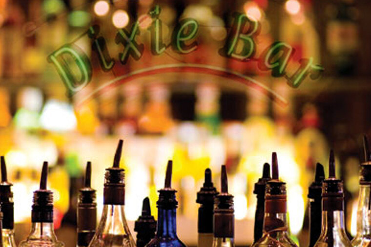 Bottles of liquor are lined up in front of a dixie bar sign