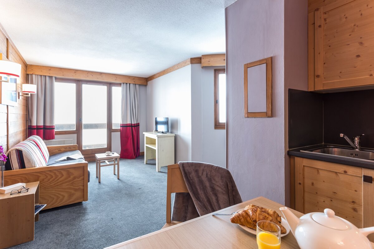 A living room with a couch and a table with a plate of croissants and a glass of orange juice