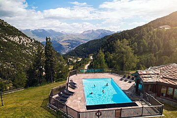 People are swimming in a pool with mountains in the background