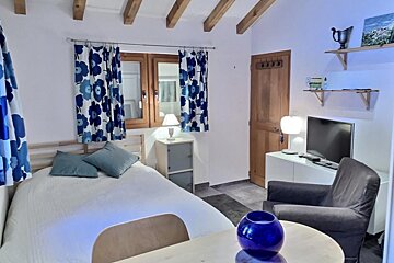 A bedroom with a bed a chair and a television