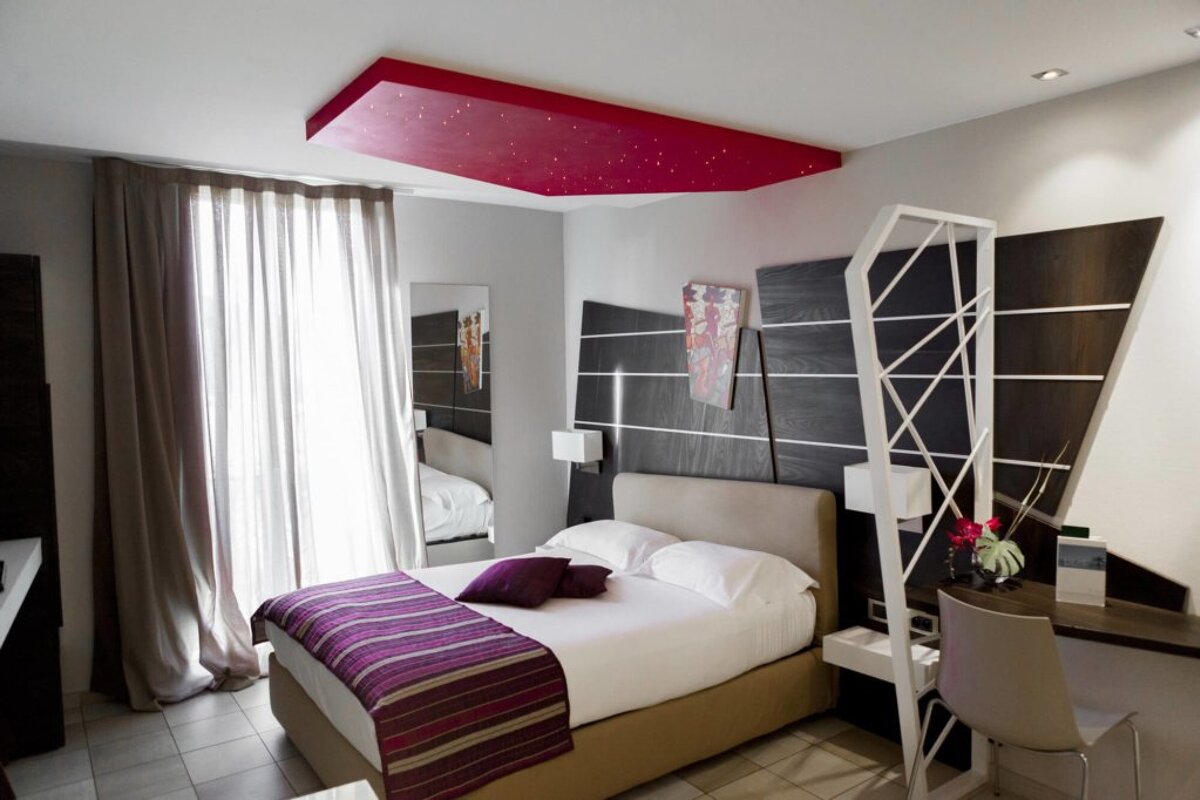 A hotel room with a bed and a red ceiling