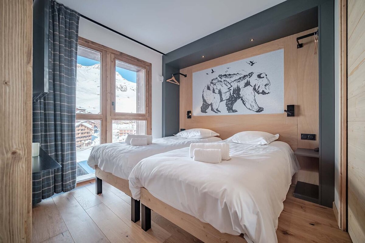 A bedroom with two beds and a bear painting on the wall