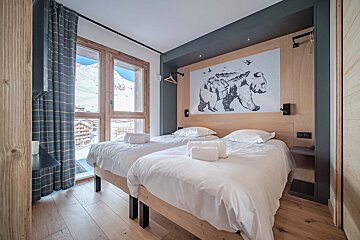 A bedroom with two beds and a bear painting on the wall