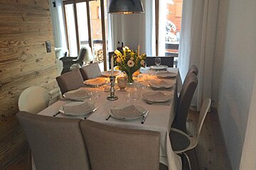 A dining room table with plates glasses and a vase of flowers