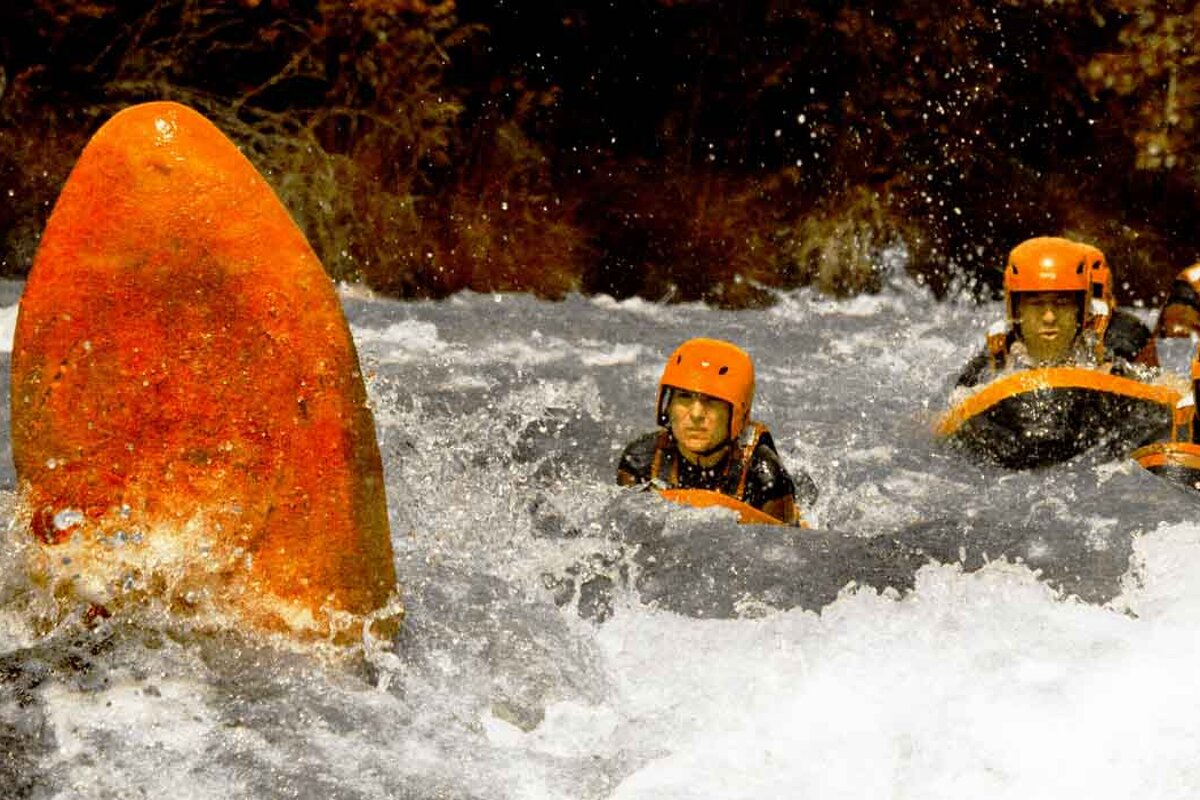A man in an orange helmet is swimming in a river