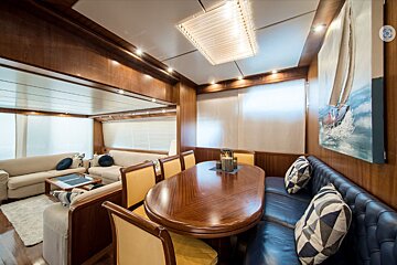 A living room with a table and chairs and a painting of a sailboat on the wall