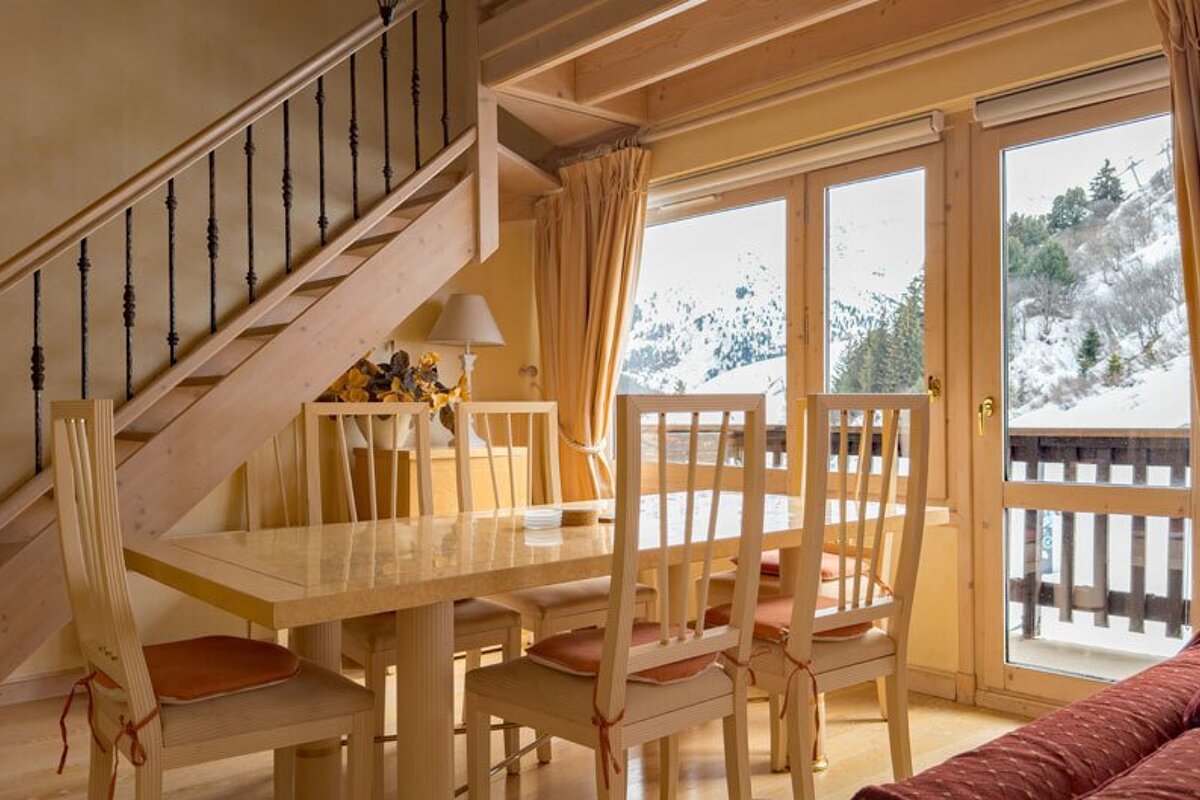 A dining room with a table and chairs under a staircase