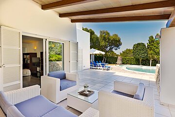 A patio with chairs and a table in front of a pool