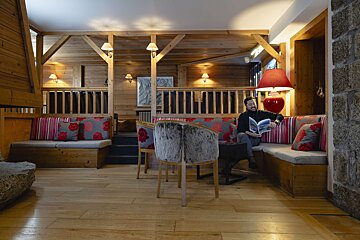 A man sits in a chair reading a magazine