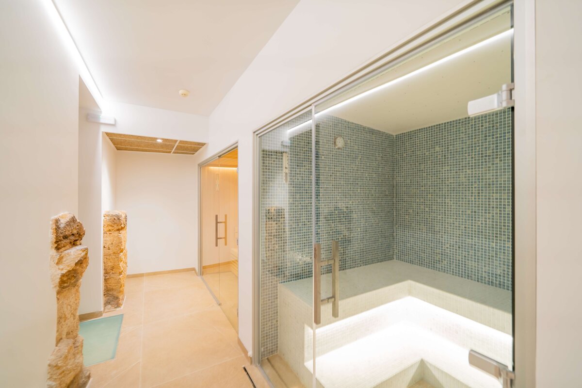A bathroom with a glass door and a tiled wall