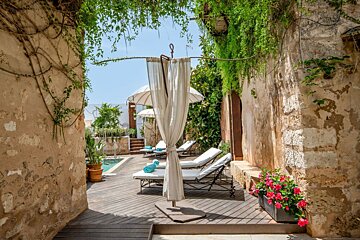 A white umbrella is hanging from a metal pole on a wooden deck