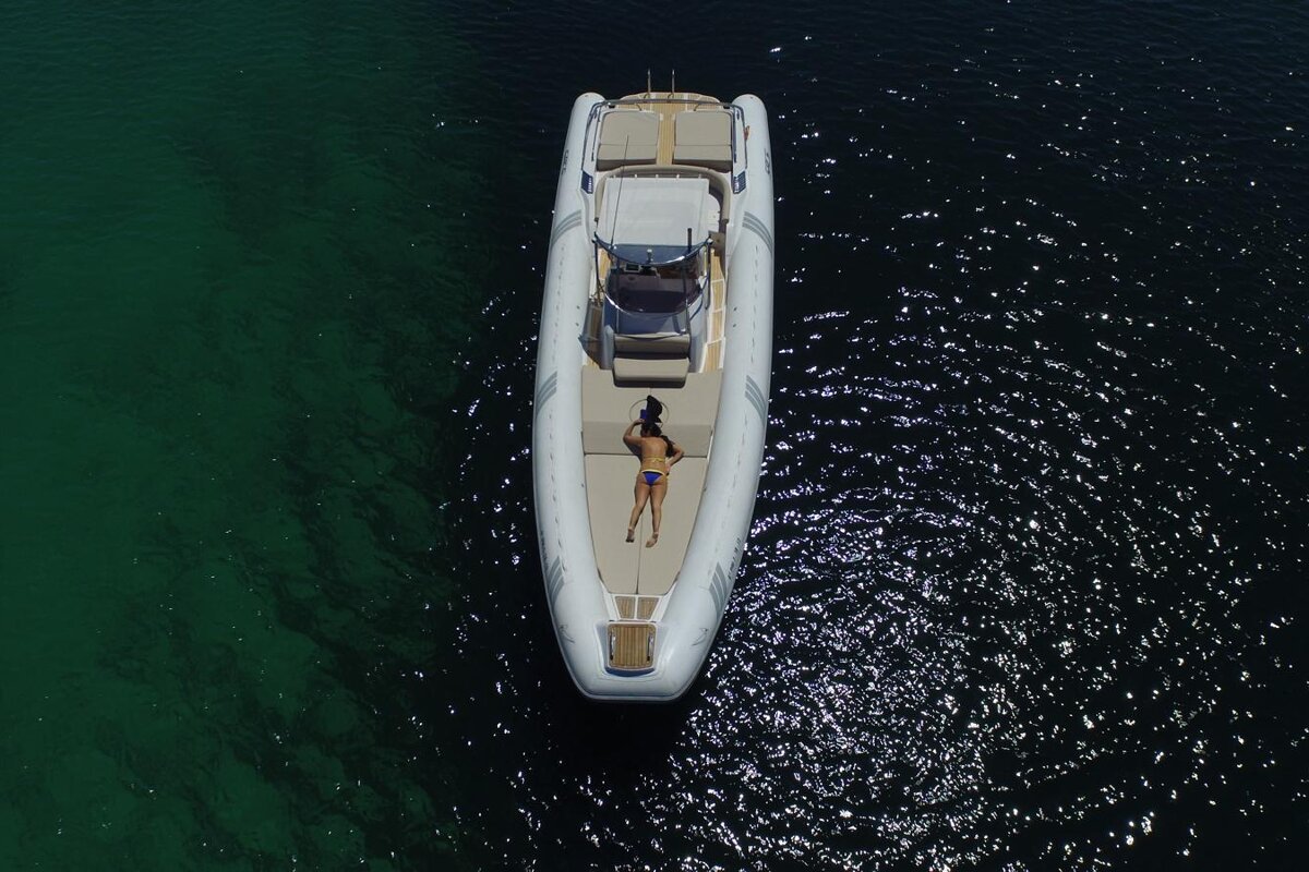 A woman is laying on the back of a boat in the water
